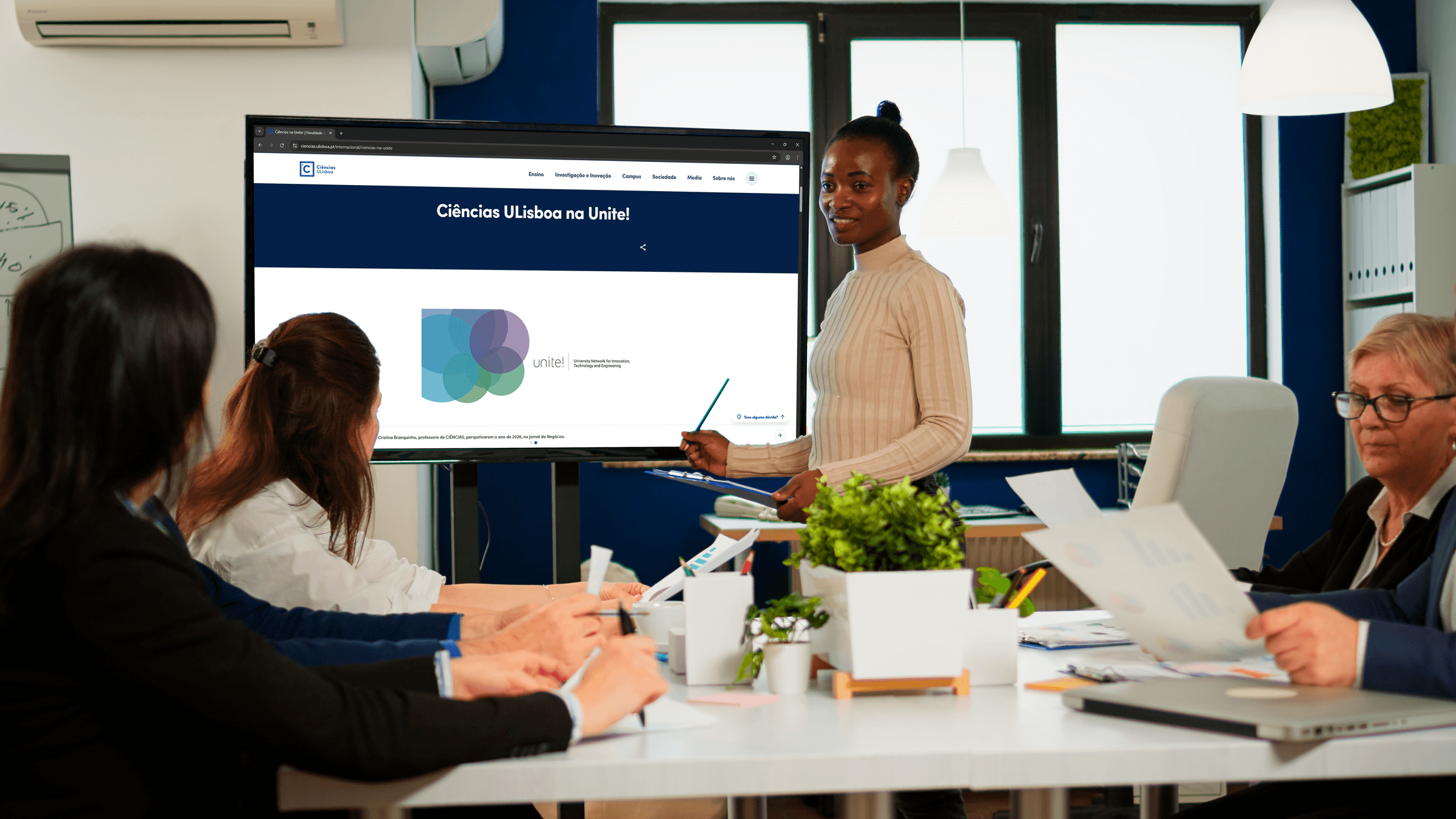 Reunião de trabalho, com monitor a mostrar informação relacionada com a Unite!