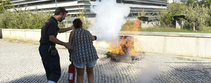 Bombeiro e participante a apagar um fogo com extintor no campus