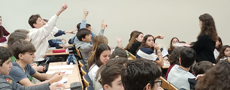 Alunos com mãoes no ar num sala de aula