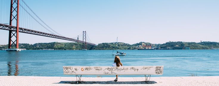 Mulher sentada em banco junto ao rio Tejo