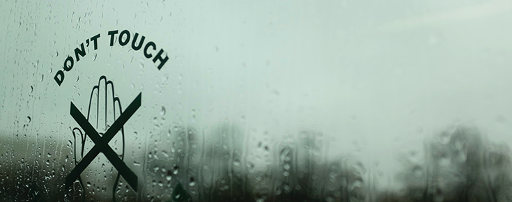 Janela com o símbolo "Don´t touch", com vista para dia chuvoso